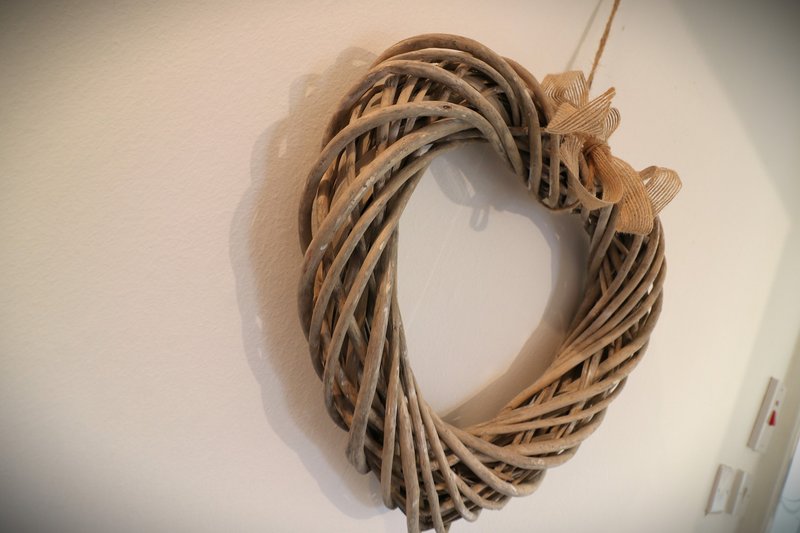 Woven wicker heart-shaped wreath decoration hanging on white wall