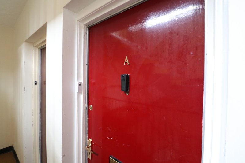 Hallway with red apartment door marked with letter A and metal door hardware