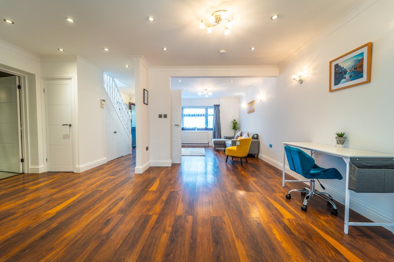 Open-plan living space with wooden flooring, white walls, recessed lighting, and modern furnishings