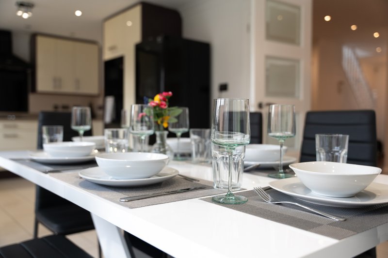 Modern dining table set with place settings, glasses, and fresh flowers in vase