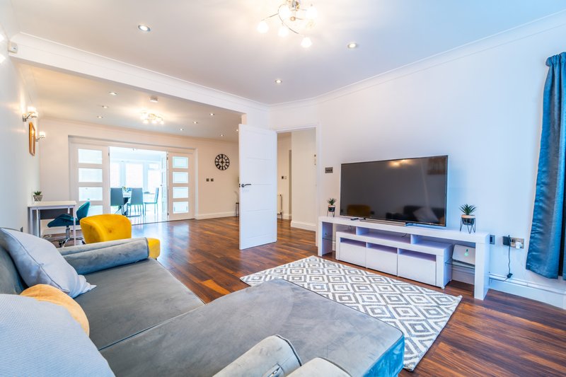 Modern living room with sofa, TV unit, wooden floors and blue accent furnishings