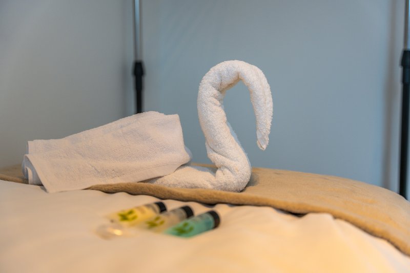 Bathroom detail with rolled white towel swan and folded towel on countertop