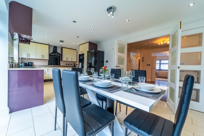 Modern open-plan kitchen and dining area with dining table, blue chairs and fitted kitchen
