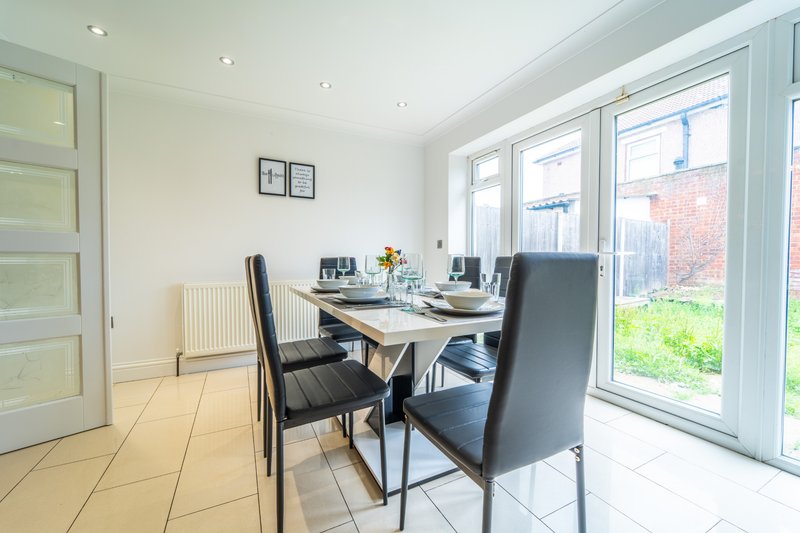 Home office with desk, black chairs, radiator and garden view through patio doors