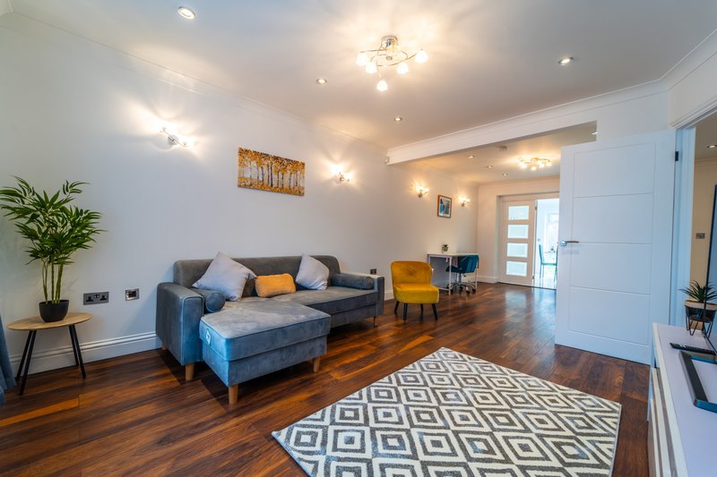 Spacious living room with blue sofa, wooden floors, potted plant and modern lighting