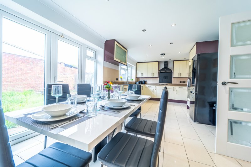 Open-plan kitchen and dining area with dining table, modern kitchen units, and garden view through large windows