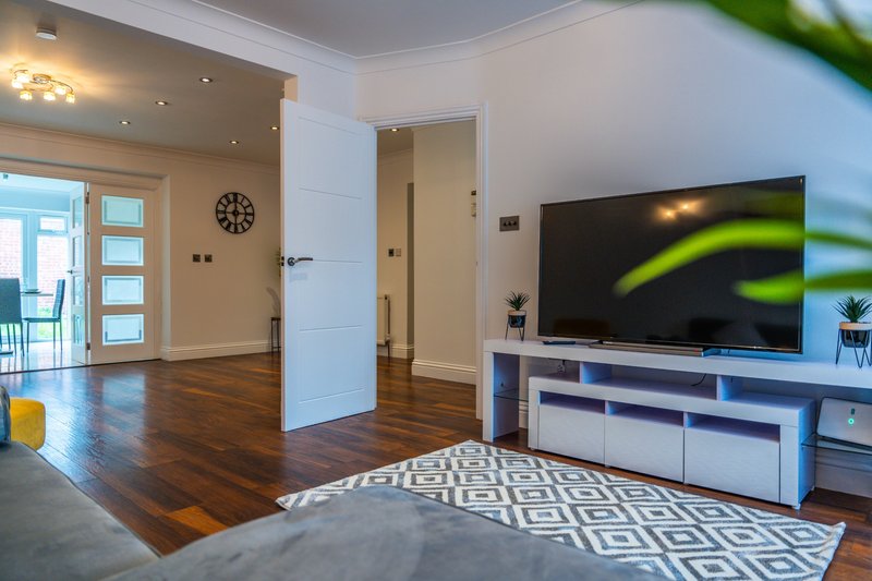Modern living room with wooden floors, TV unit, geometric rug and open-plan layout