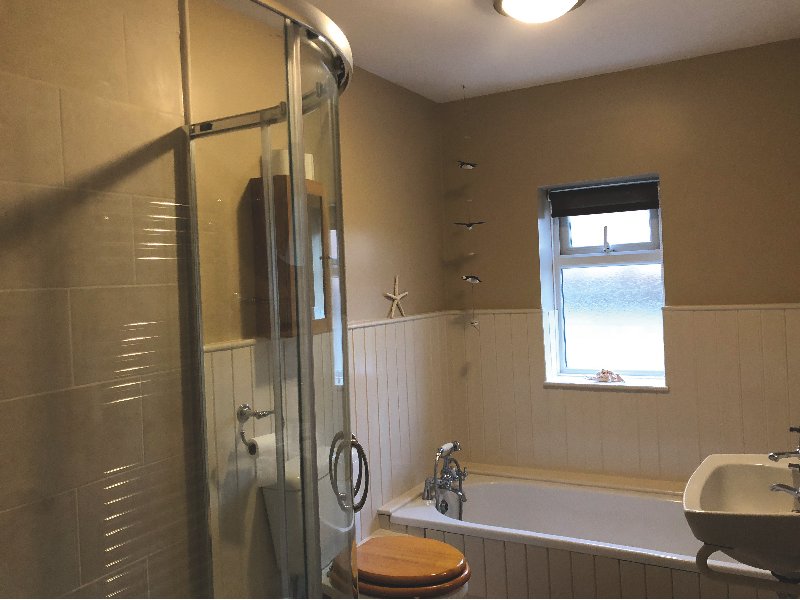 Bathroom with shower enclosure, bathtub, window and beige tile walls