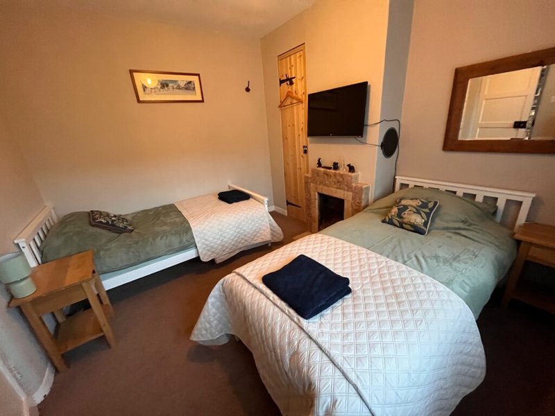 Bedroom with three single beds, wooden chair, TV, fireplace and mirror