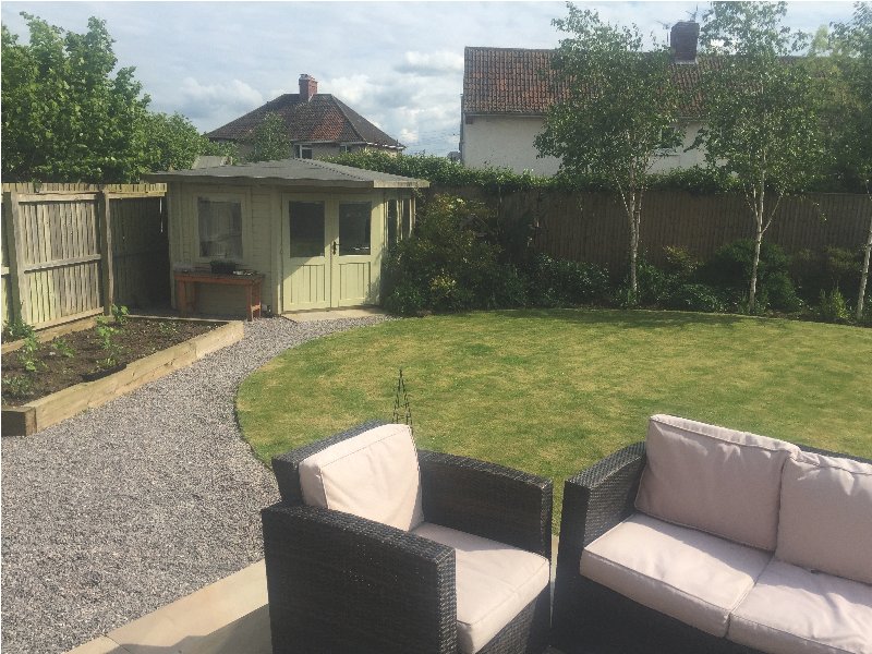 Garden with patio seating, lawn, garden shed, and neighbouring houses