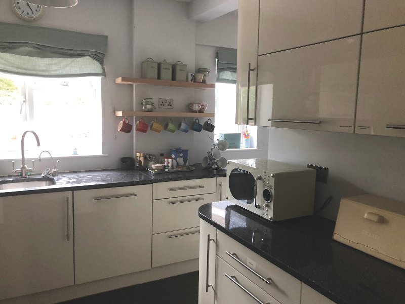 Modern kitchen with cream cabinets, black countertop, sink, and small appliances on island