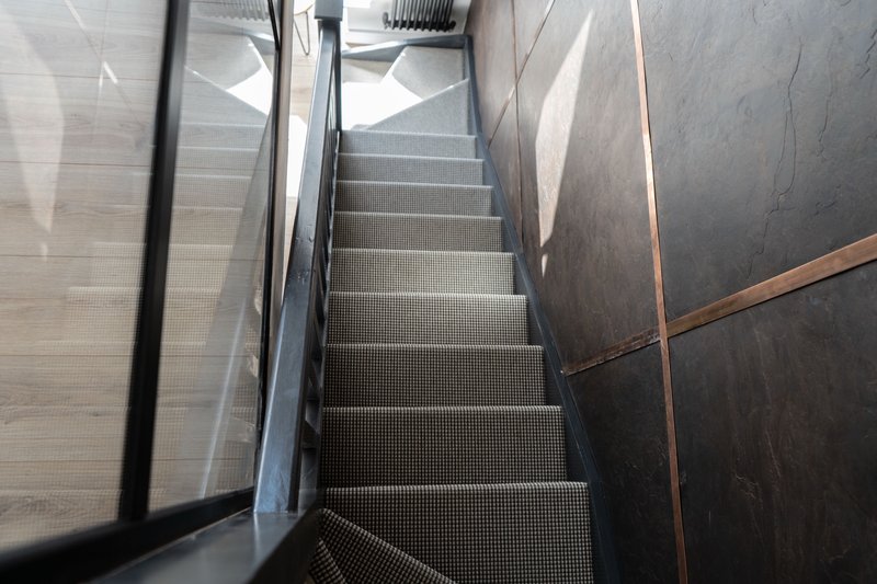 Metal staircase with handrails and industrial flooring, viewed from above