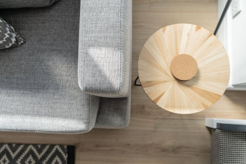 Overhead view of grey upholstered sofa with wooden pendant lamp and patterned rug