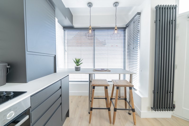 Modern kitchen with grey cabinetry, bar seating, pendant lights and large window