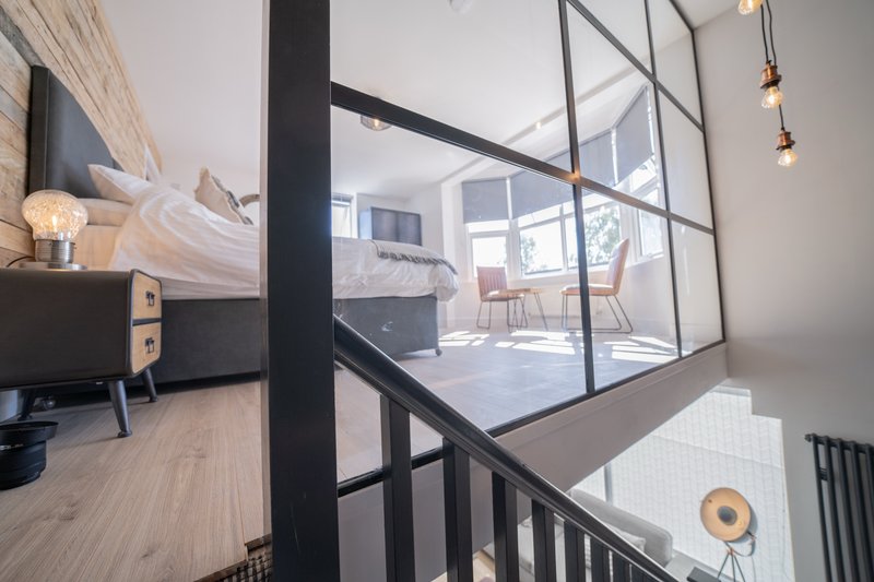Modern open-plan loft with black steel partitions, wooden flooring, staircase and contemporary furnishings