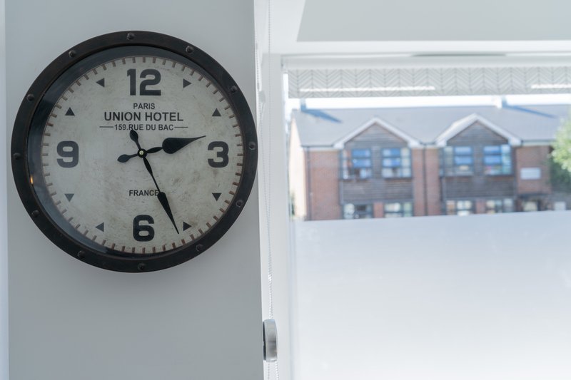 Wall clock with Union Hotel branding beside window overlooking brick residential building