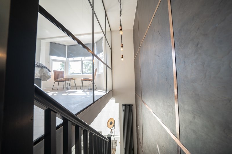 Modern staircase with black metal railing and pendant lights overlooking open-plan living area