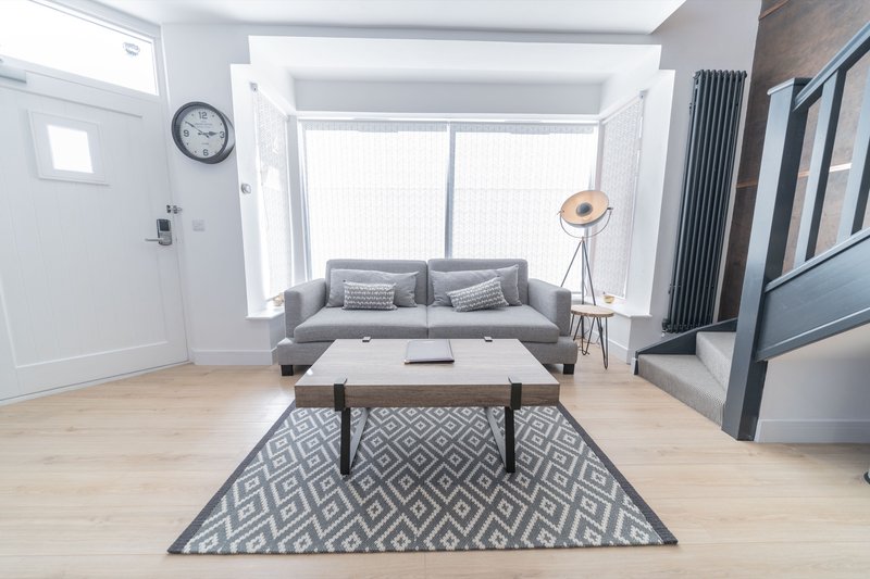 Modern studio bedroom with sofa bed, wooden floor, coffee table and large windows