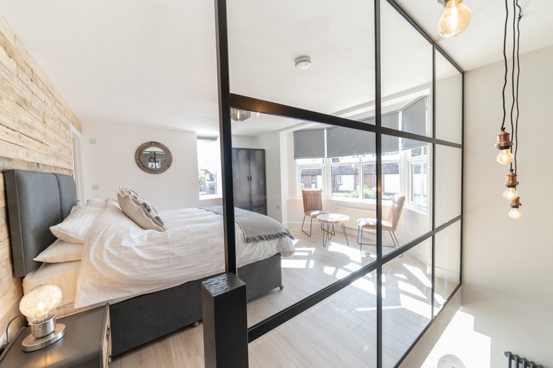 Modern bedroom with double bed, glass partition wall, pendant lights and city view