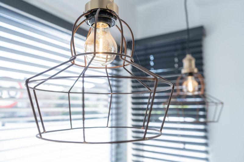 Industrial pendant light fixture with wire cage shade, modern interior lighting detail