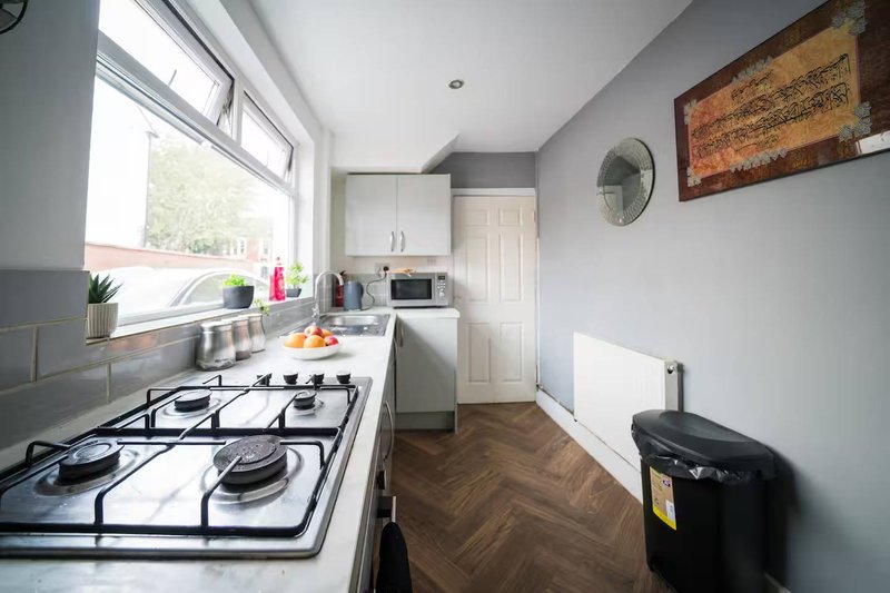 Modern kitchen with gas cooktop, white cabinetry, herringbone wooden floor and window