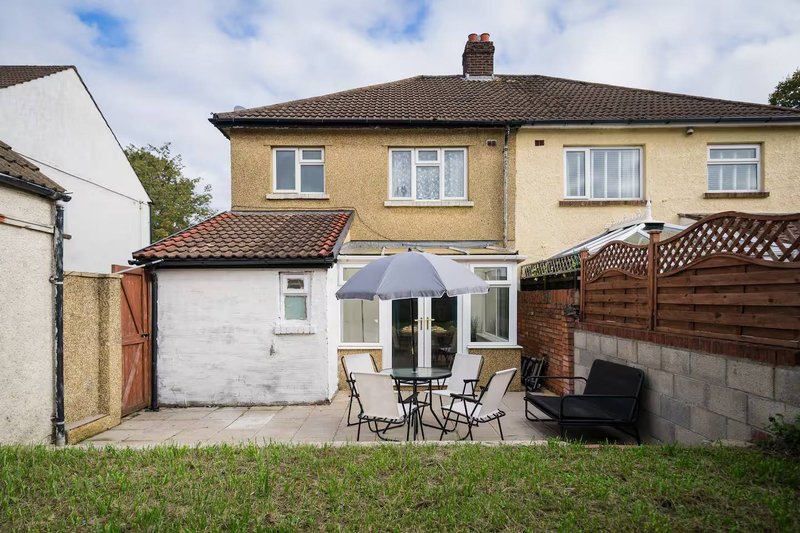 Semi-detached house with cream-colored exterior, garage, patio area with umbrella and seating