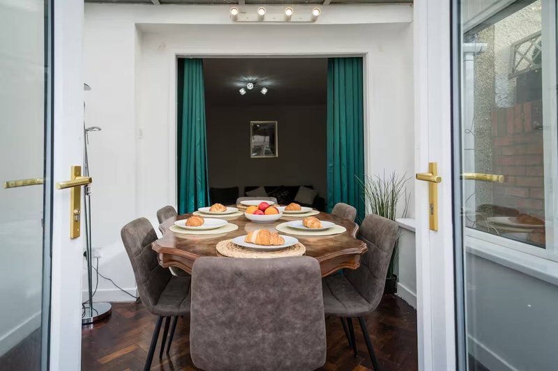 Dining room with round table, four gray chairs, place settings, and teal curtains