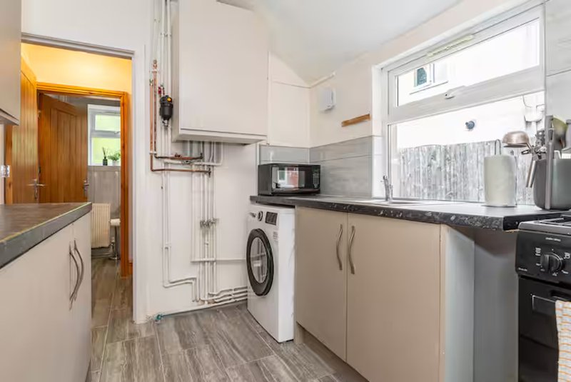 Modern kitchen with white cabinetry, stainless steel appliances, washing machine and window view