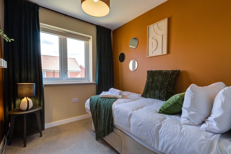 Modern bedroom with double bed, orange accent wall, dark curtains and window view