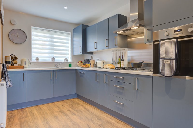 Modern kitchen with blue cabinetry, wooden flooring, stainless steel appliances and window