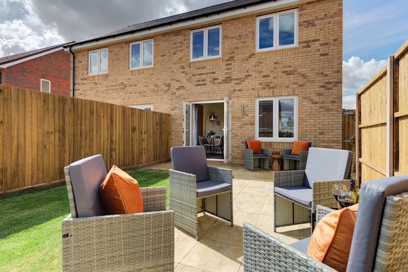 Brick house with patio garden, rattan seating, and manicured lawn