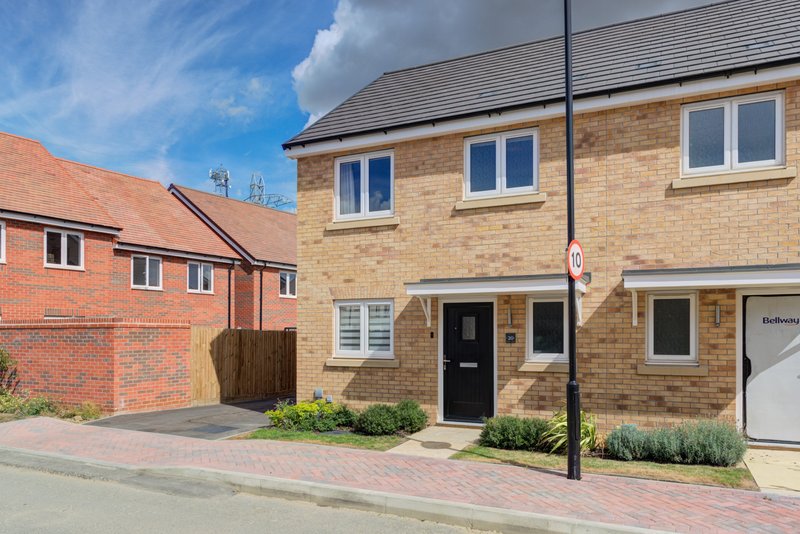 Modern brick townhouse with driveway, black front door, and adjacent red brick property