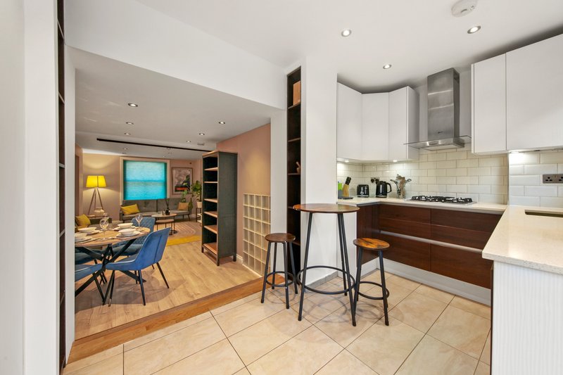 Modern kitchen and living area with wooden flooring, bar seating, and open-plan design