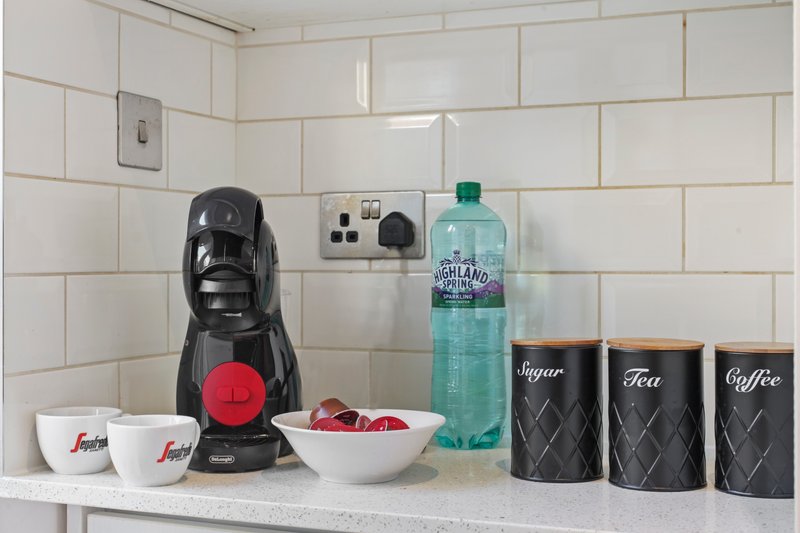 Kitchen counter with coffee maker, water bottle, storage canisters and white subway tile backsplash