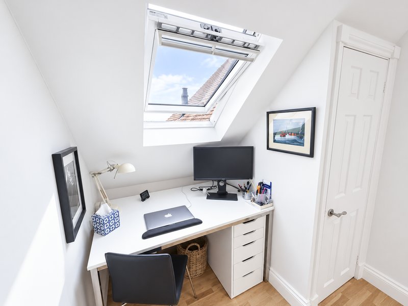 Compact home office with desk, computer monitor, skylight window and wooden flooring