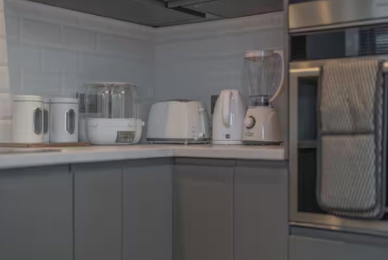 Modern kitchen counter with white appliances, blender, and stainless steel refrigerator