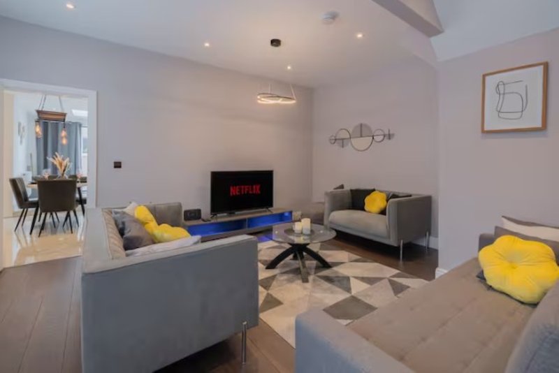 Modern living room with gray sofas, yellow cushions, blue coffee table and wall-mounted TV