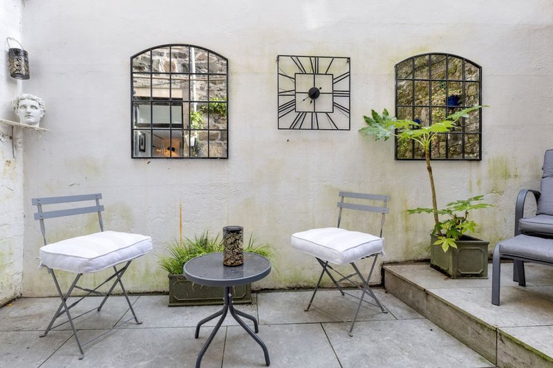 Outdoor patio seating area with two chairs, small table, decorative mirrors and potted plants