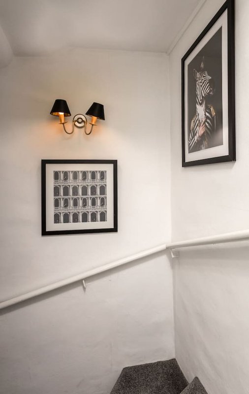 Stairwell with white walls, wall-mounted sconce lamp, and framed artwork