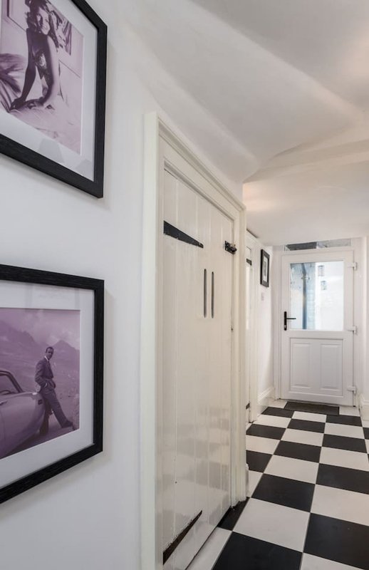 Hallway with black and white checkered floor, white doors, and framed purple-toned wall art