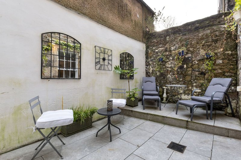 Paved courtyard with seating area, potted plants, decorative mirrors and stone walls