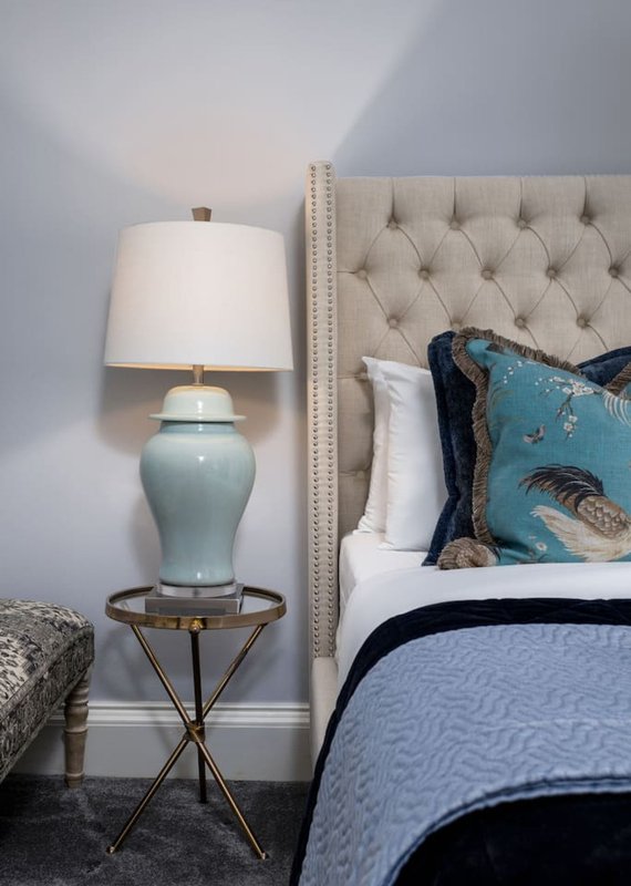 Bedroom with upholstered headboard, bedside lamp, decorative pillows and side table