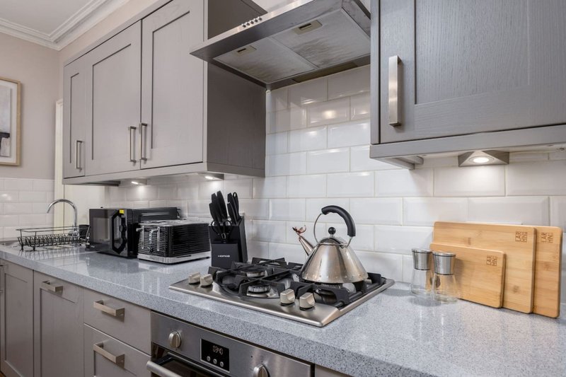 Modern kitchen with grey cabinets, white subway tile backsplash, stainless steel appliances and granite countertop