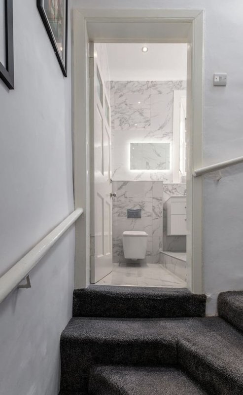 Bathroom with marble walls and floor, toilet, and sink viewed through open doorway