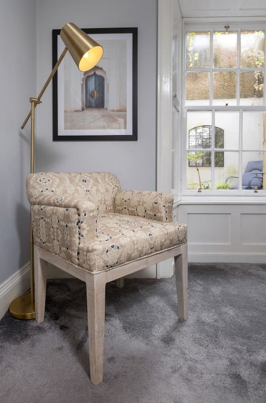 Bright reading nook with upholstered armchair, brass floor lamp, and large window with natural light