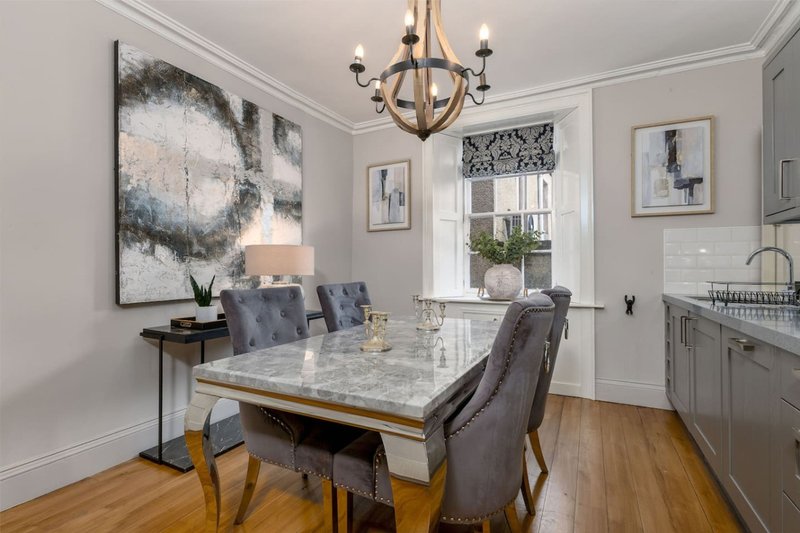 Modern dining room with marble table, upholstered chairs, chandelier and wall art