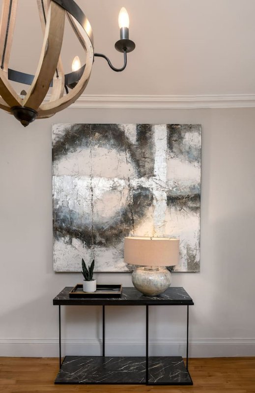 Modern entryway with abstract wall art, black console table, decorative candle and plant