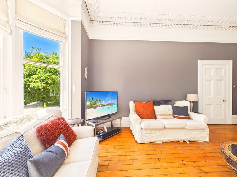 Bright living room with cream sofa, wooden floor, large window and gray accent wall