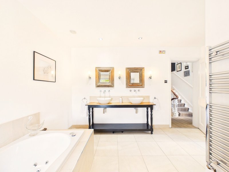 Spacious bathroom with double vanity, bathtub, heated towel rail and framed mirrors