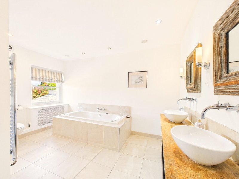 Luxury bathroom with freestanding bathtub, double vanity sink, heated towel rail and window